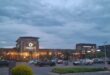 Shopping center at dusk with lit signs for Groblersdal Mall, Woolworths, and McDonald's. Cars parked in the lot, under a cloudy sky, creating a calm atmosphere.