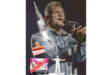 Steve Hofmeyr passionately sings on stage, eyes closed, with a microphone. A "Cancelled" stamp overlaps a colorful event poster below. The mood is intense.