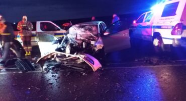 A scene of a crash with damaged vehicles and police cars.