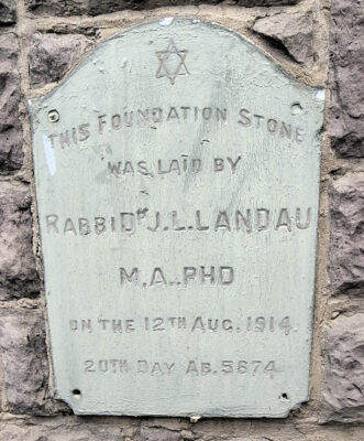 Plaque with Star of David on a stone wall reads: "Foundation stone laid by Rabbi Dr. J.L. Landau, M.A. PhD, on 12th Aug. 1914, 20th day Ab 5674."