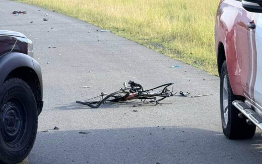 A damaged bicycle lies in the middle of a road between two parked cars, with scattered debris around. The scene suggests a recent accident, conveying a tense atmosphere.