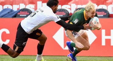 In a rugby match, one player struggles to take the ball from another, highlighting the intensity of the game.