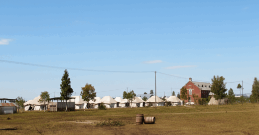 A grassy field featuring several tents set up for an outdoor event or camping.