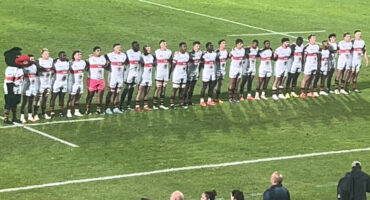 A group of Tuks rugby players standing together on a rugby field, dressed in Tukkies rugby shirts, ready for a game.