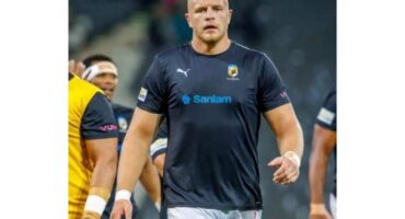 A rugby player walks confidently across the field, showcasing their athleticism and focus on the game ahead.