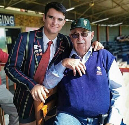 A man sitting beside an older man in a stadium, both focused on the event happening in front of them.
