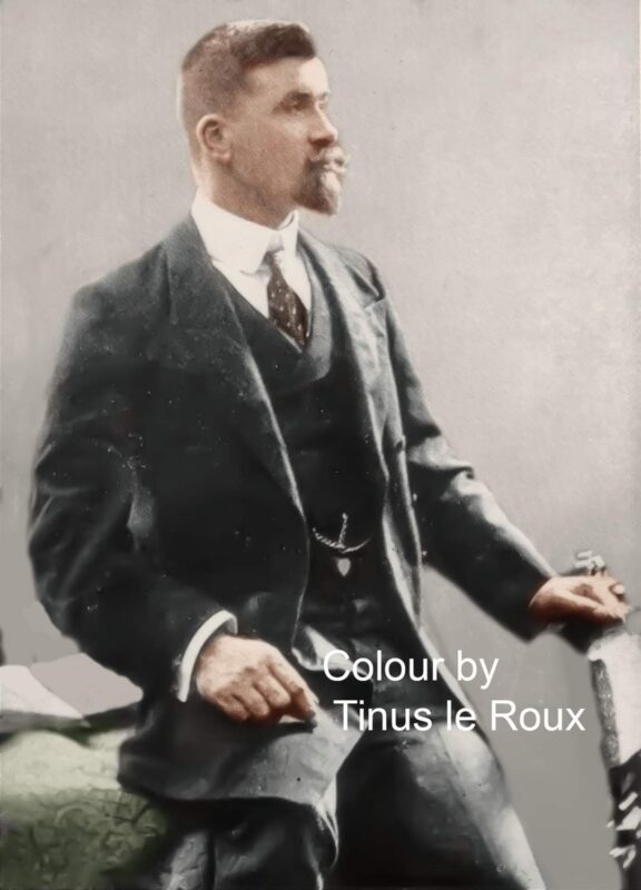 A man in an early 20th-century suit, seated and gazing to the side, exudes confidence. Image is colorized, with "Colour by Tinus le Roux" noted.