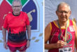 Elderly man in athletic gear stands proudly before sports-themed backdrop. He wears medals, exuding accomplishment and joy, symbolizing athletic success.