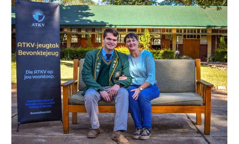 A man and woman sit on a bench in front of a building, engaged in conversation and enjoying their surroundings.