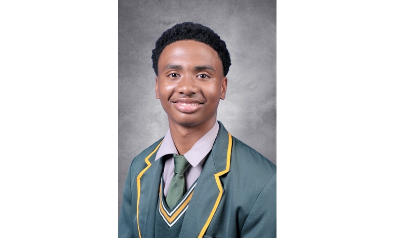 Smiling young person in a school uniform with green blazer and yellow trim, against a gray backdrop. The tone is positive and formal.