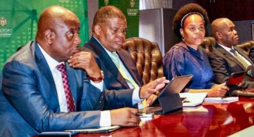 Four people sit at a polished table, focused and engaged, with tablets and notes. A backdrop displays "Limpopo Provincial Government."