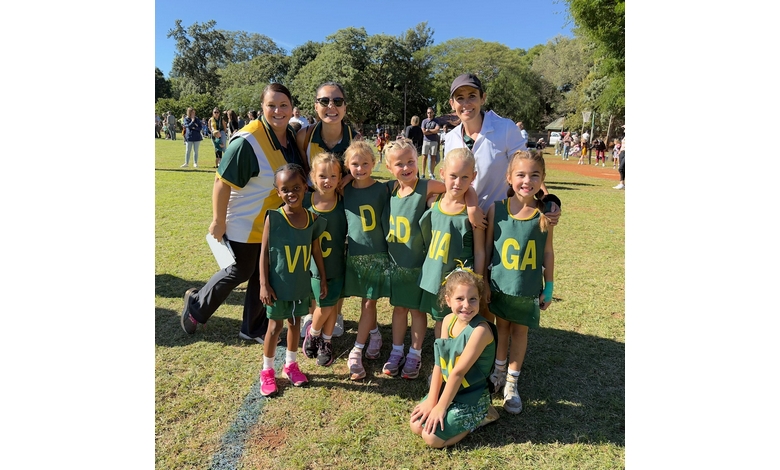 A group of young girls in green uniforms smiling and posing together for a photo.