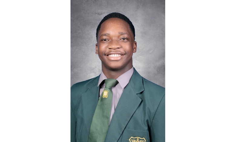 A smiling young person wearing a green blazer with an emblem and a matching tie. The gray background highlights a confident, professional appearance.