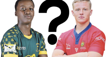 Two rugby players stand facing forward, one in a green jersey and the other in red, with a large question mark between them, suggesting a comparison.