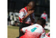 A young boy in a red and white sports jersey stands with hands covering his face, conveying emotion. Another child with a number 4 jersey is kneeling.