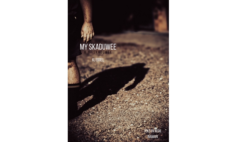 A shadow of a person on a gravel surface, with one visible leg on the left. The text reads "My Skaduwee," suggesting introspection or mystery.
