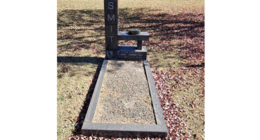 Gravesite with a modern headstone labeled "SMIT." The grave is surrounded by fallen leaves, conveying a serene and contemplative autumn setting.