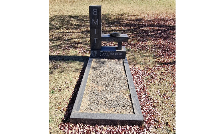 Gravesite with a modern headstone labeled "SMIT." The grave is surrounded by fallen leaves, conveying a serene and contemplative autumn setting.