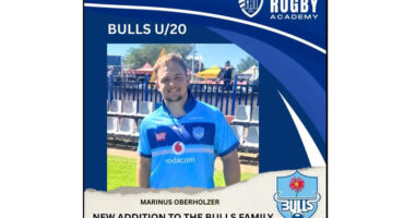 Young rugby player in a blue Bulls U/20 jersey smiles, standing outdoors. The text celebrates his addition to the Bulls family. Bright, sunny day.