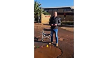 A man standing by a huge pothole.