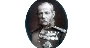 Portrait of a bearded man wearing military medals, showcasing pride and honor in his expression.
