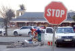 A stop sign alongside a man and woman in work attire, actively performing maintenance tasks on the roadside.