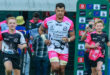 A rugby player in motion, accompanied by two young supporters, demonstrating collaboration and energy in a competitive game.