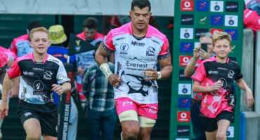 A rugby player in motion, accompanied by two young supporters, demonstrating collaboration and energy in a competitive game.
