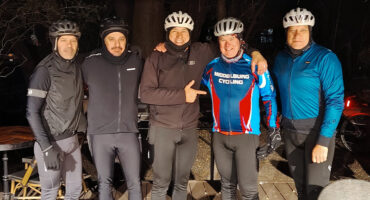 A group of men in cycling gear smiling and posing together for a photo outdoors