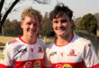 Two young men wearing red and white jerseys stand side by side, smiling at the camera.