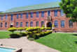 A large brick building stands prominently with a fountain in front, creating an inviting outdoor space.