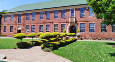 A large brick building stands prominently with a fountain in front, creating an inviting outdoor space.