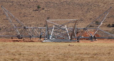 A large metal structure with intricate designs and beams, set against a clear blue sky.