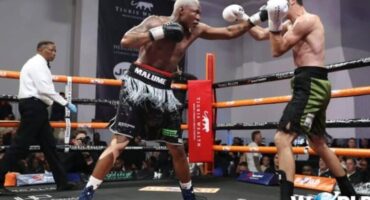 Two boxers engage in a competitive match inside a boxing ring, showcasing their athleticism and skill.