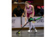 A woman in a pink uniform skillfully playing field hockey.