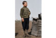 A boy stands beside a large pile of bricks, looking up with curiosity and interest.