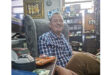 A man in a chair, showcasing a wristwatch, exudes a calm and thoughtful demeanor.