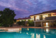 A serene pool illuminated by dusk light, situated in front of a modern building with a tranquil atmosphere.