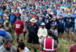 A large assembly of individuals standing together in a grassy field, showcasing camaraderie and community spirit.