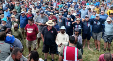 A large assembly of individuals standing together in a grassy field, showcasing camaraderie and community spirit.