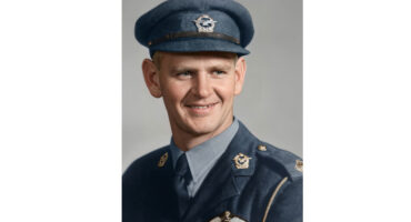 A smiling man in a uniform and cap, exuding a friendly and approachable demeanor.
