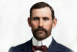 Portrait of a bearded man wearing a bow tie, smiling confidently at the camera.