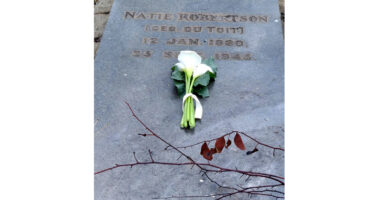 Natalie Portman's grave, adorned with floral tributes, displaying her name and dates in a peaceful cemetery setting.