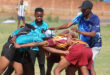 A group of young men engaged in a rugby match on a grassy field, showcasing teamwork and athleticism.