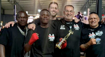 A group of men proudly displaying their boxing trophies while posing for a photo together.