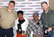 Four individuals proudly display their awards while smiling joyfully at the camera.