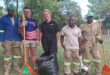 A group of five men and one woman, each holding shovels and trash bags, engaged in a community cleanup effort.