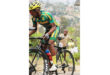 A cyclist in a vibrant green and yellow outfit pedals down a path, enjoying the outdoors.