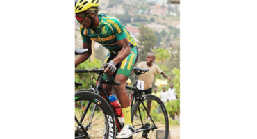 A cyclist in a vibrant green and yellow outfit pedals down a path, enjoying the outdoors.
