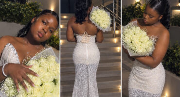 A woman in a white dress stands gracefully, holding a vibrant bouquet of flowers in her hands.